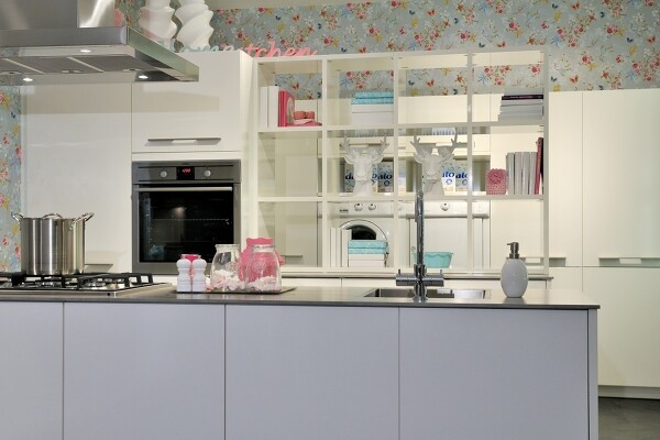 Die freistehende Theke, grifflos und matt lackiert, schafft eine ruhige Barriere zum Küchenbereich.